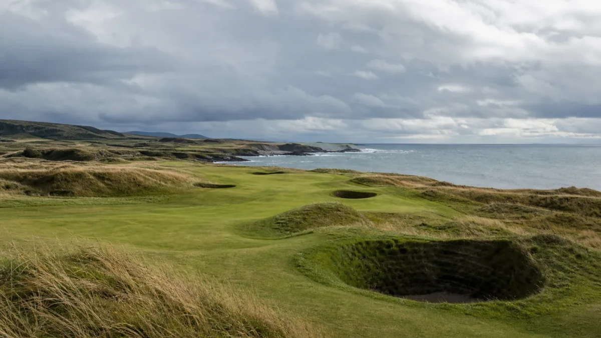 Skotsk linksbana med fairway, bunkrar och hav i bakgrunden